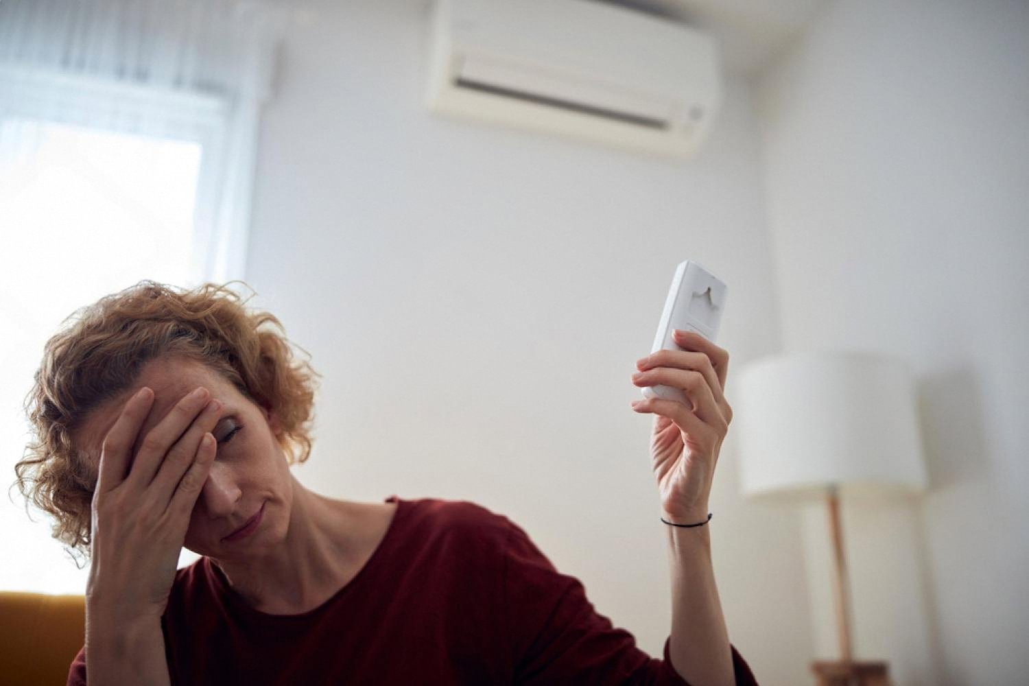 UAE homeowner looking frustrated while trying to operate a standalone air conditioner
